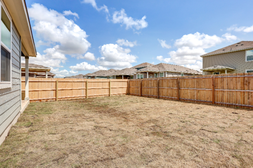 A fenced in yard with a house and mountains in the background.