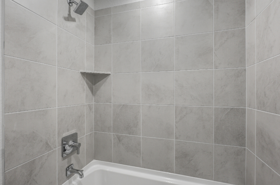 A bathroom with a bathtub and tile walls.
