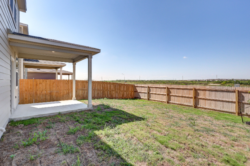 A fenced in yard with a wooden gate and a house.