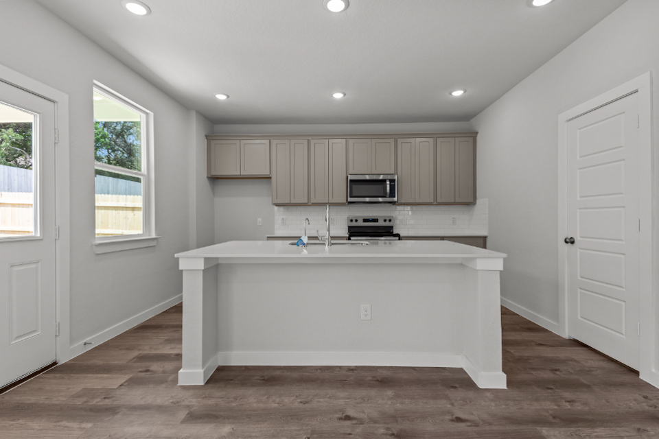 A white kitchen with a white counter top and white cabinets.
