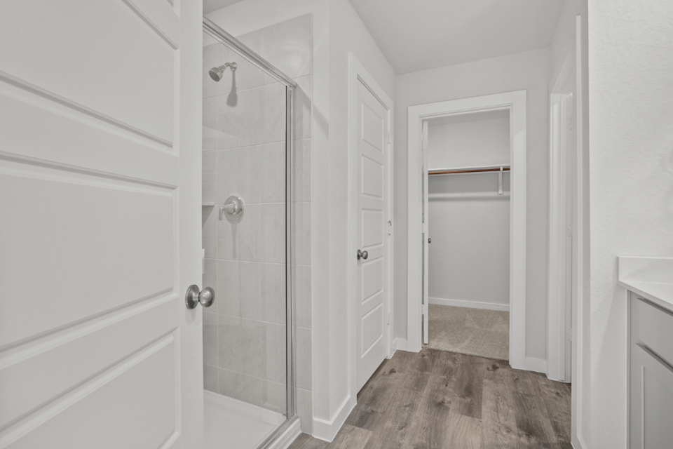 A bathroom with a shower unit and a glass door.