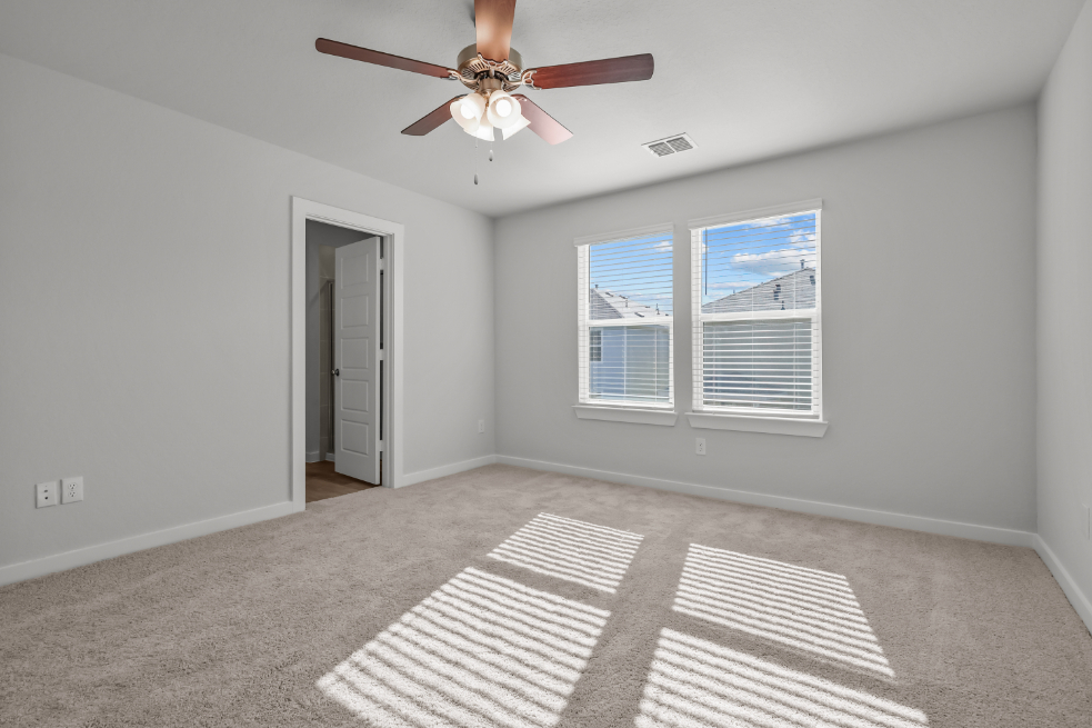 A room with a ceiling fan and a rug.