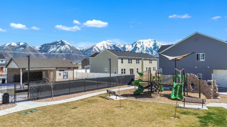 A fenced in yard with buildings and mountains in the background.