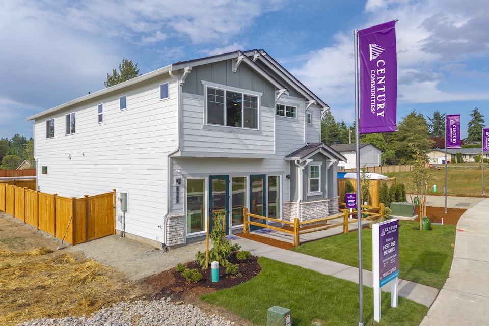 A white house with a fence and a sign in front of it.