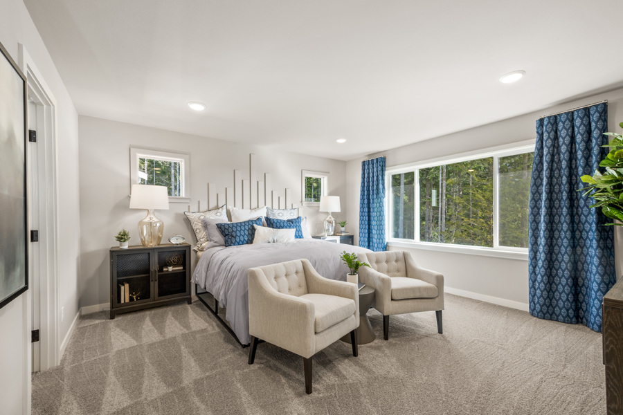 A bedroom with a bed and chairs.