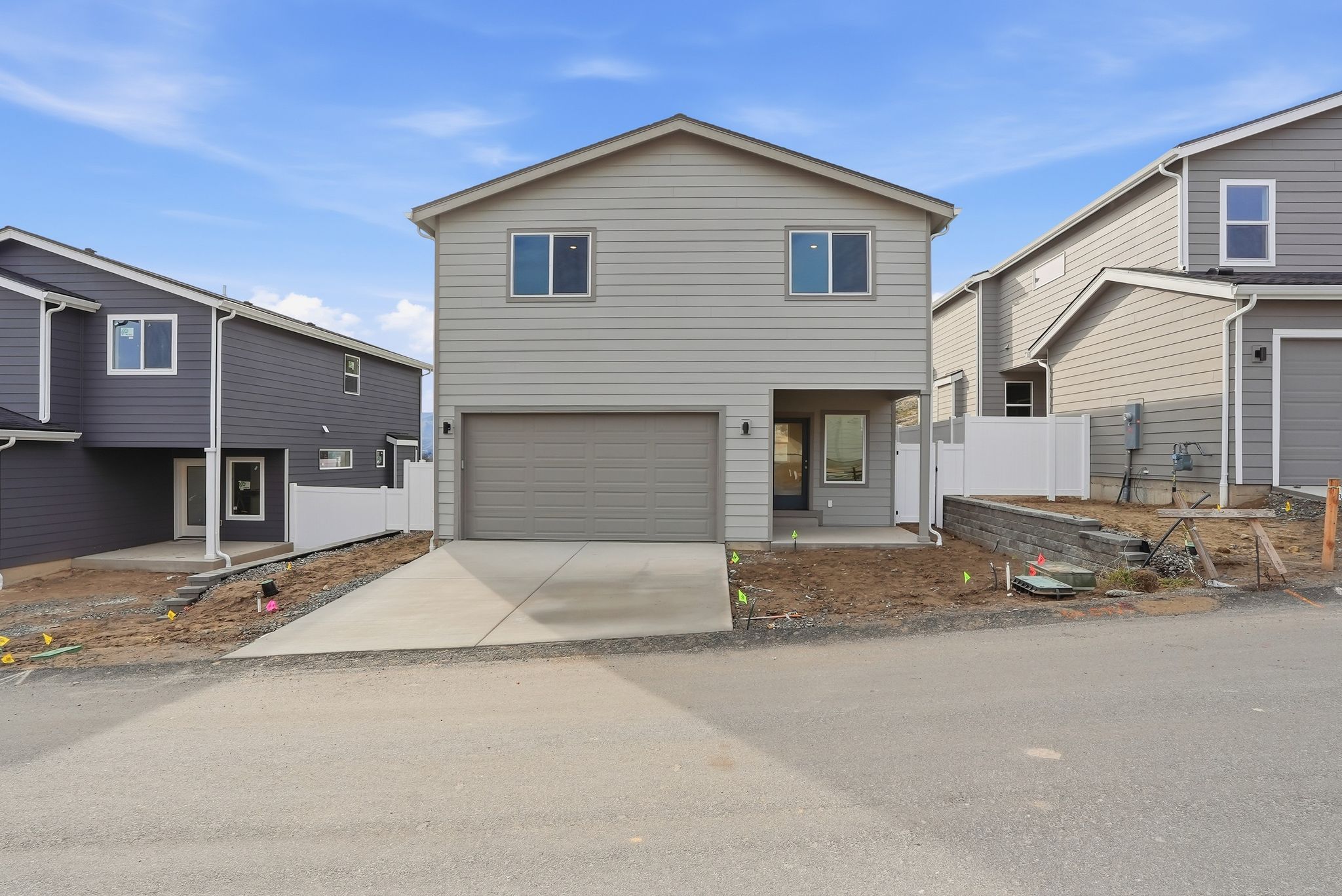 A house with garages and a dirt driveway.