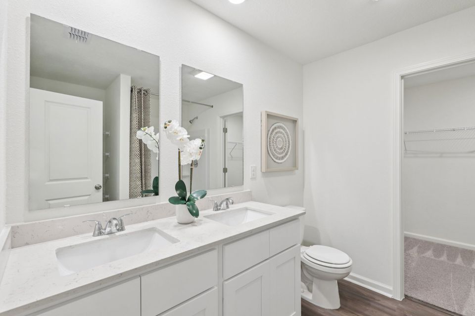 A bathroom with a sink toilet and mirror.