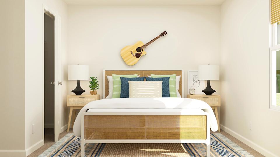 A bed with a guitar on the wall.