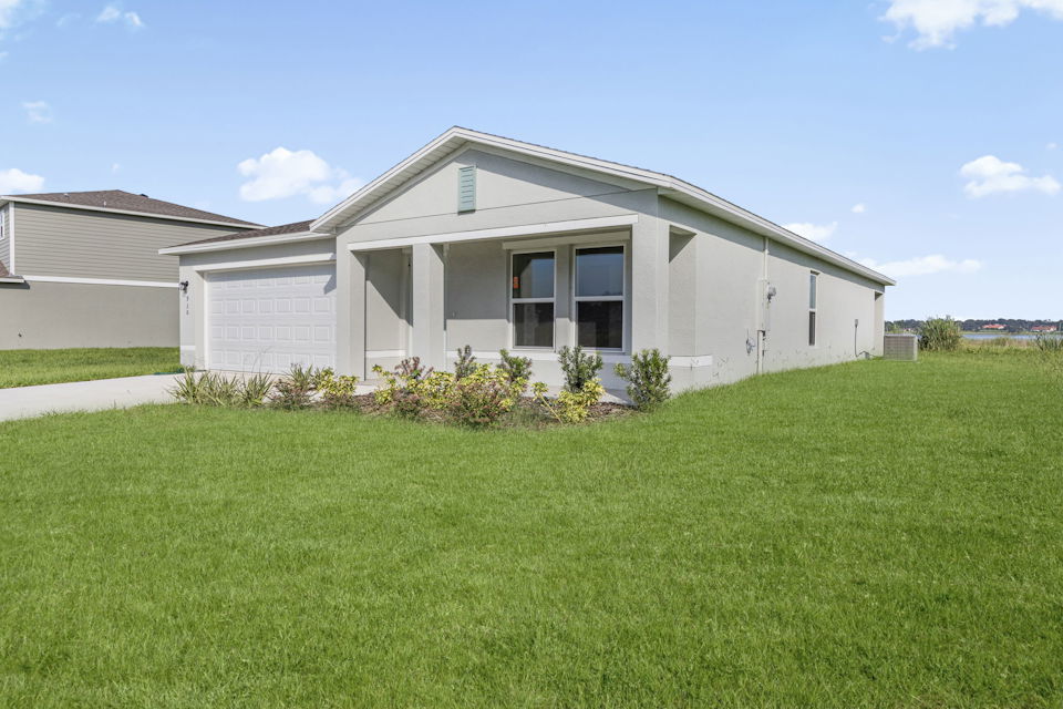 A house with a grass yard with Southfork Ranch in the background.
