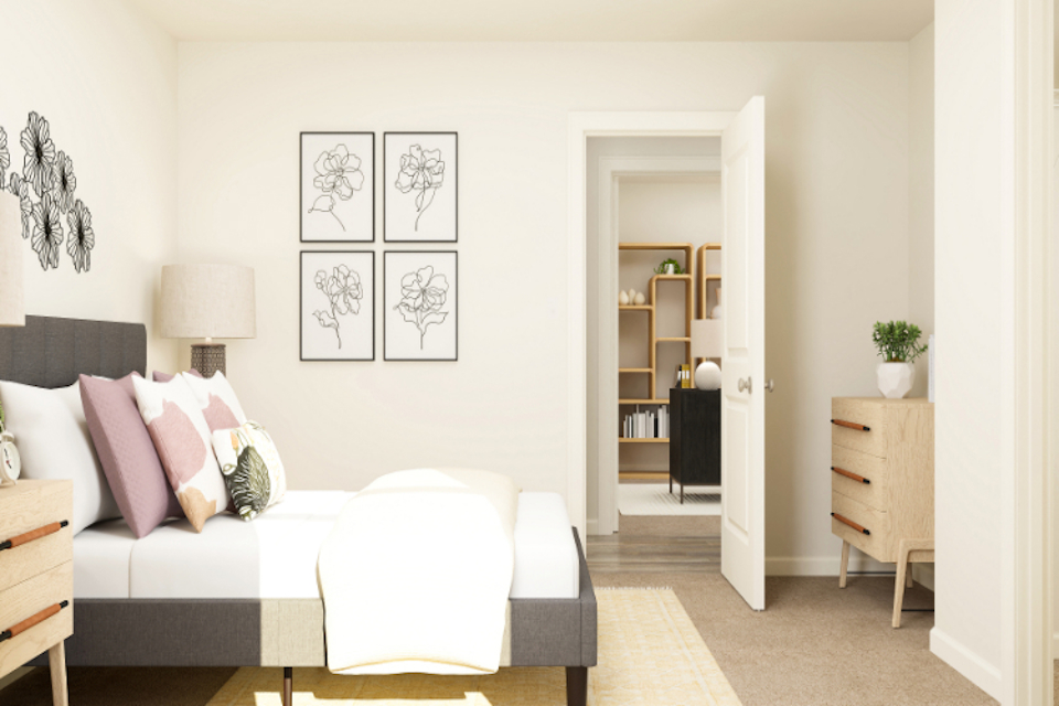 A living room with a white couch and a white wall with art on it.