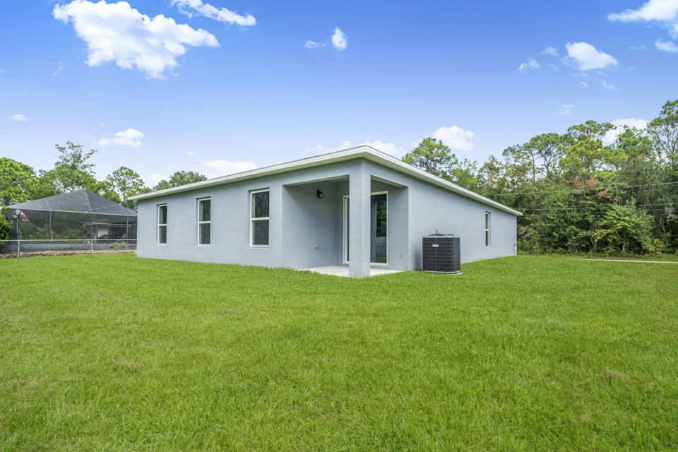 A white house with a fence and trees in the background.