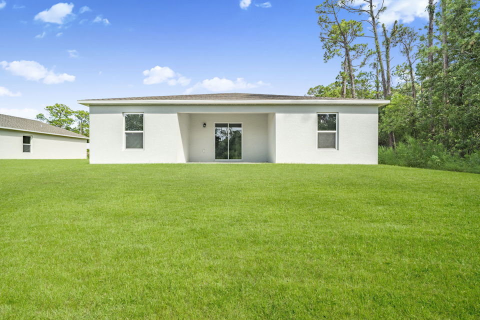 A white house with a green lawn.