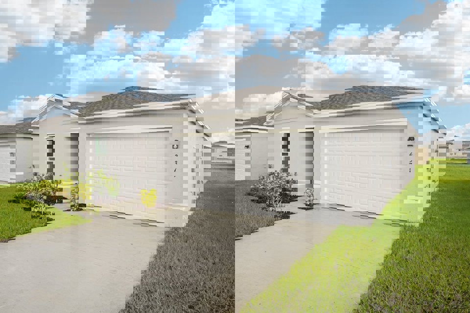 A white garage with a grass lawn.