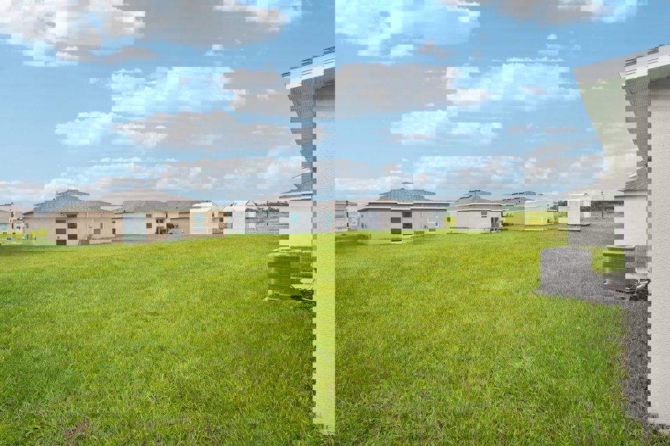 A grassy field with buildings in the background.