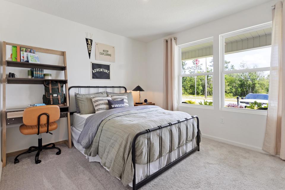 A bedroom with a bed and a chair.