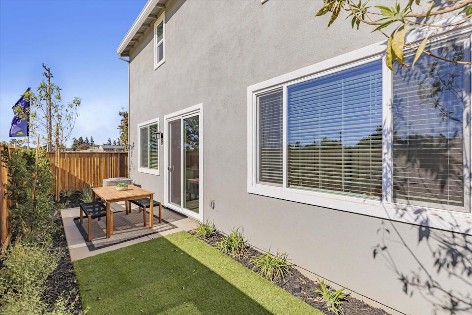 A house with a patio and a table and chairs in the front.
