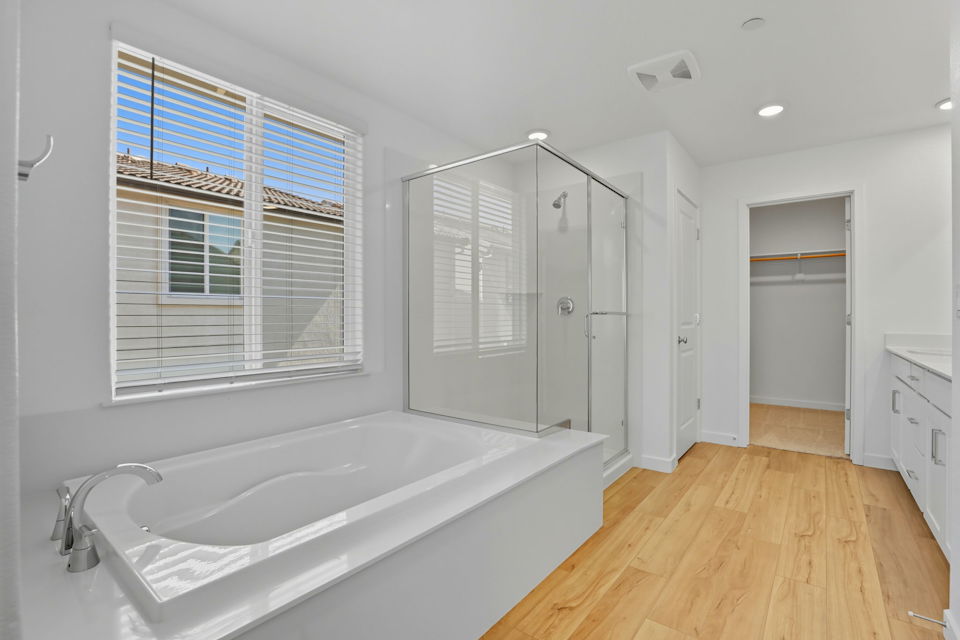 A bathroom with a tub and a shower unit.
